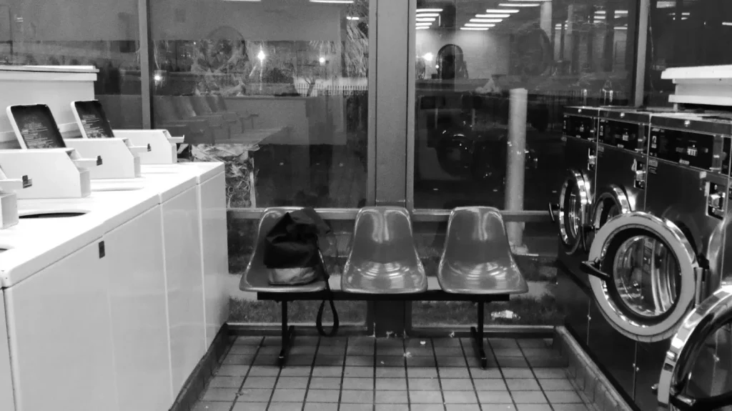 Tanda peringatan dan etiket yang tertempel di dinding sebuah coin laundry.