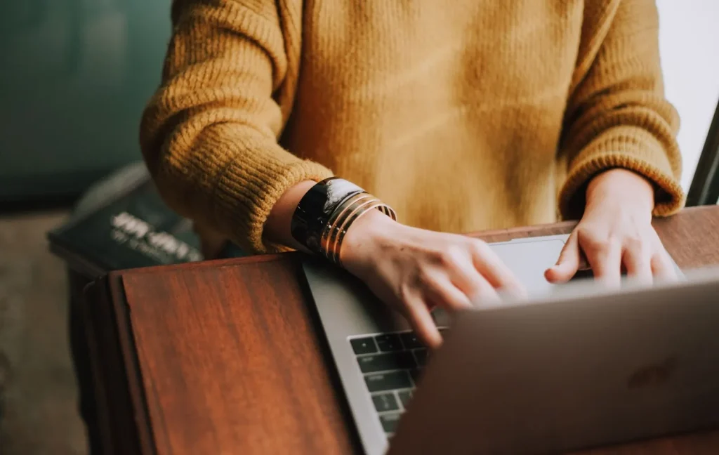 Seseorang sedang mencari lowongan kerja di laptop dengan secangkir kopi.